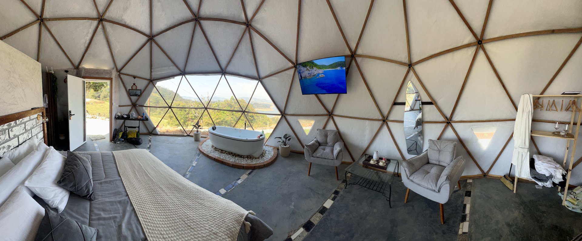 Vista panorâmica do interior do domo com cama King, hidro e sala